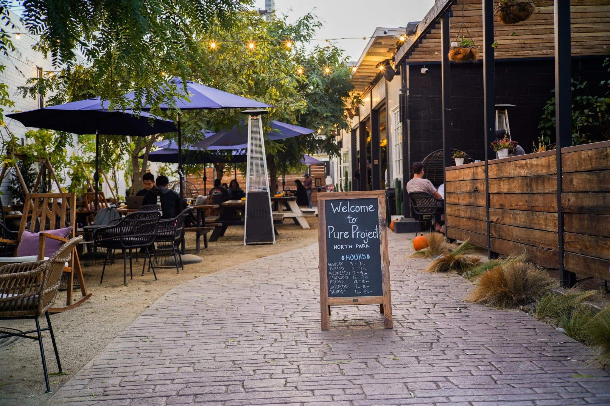 Image of the entrance to Pure Project North Park, showing the biergarten and welcoming A-frame sign
