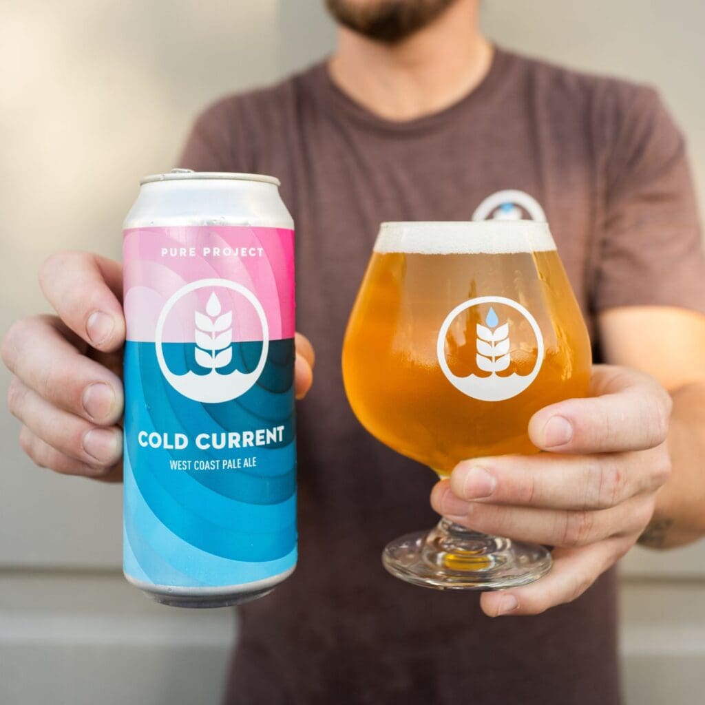 Image of person holding a can & pour of Cold Current West Coast pale ale