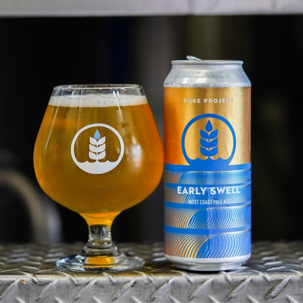 Can of Pure Project Early Swell West Coast pale ale next to glass of beer