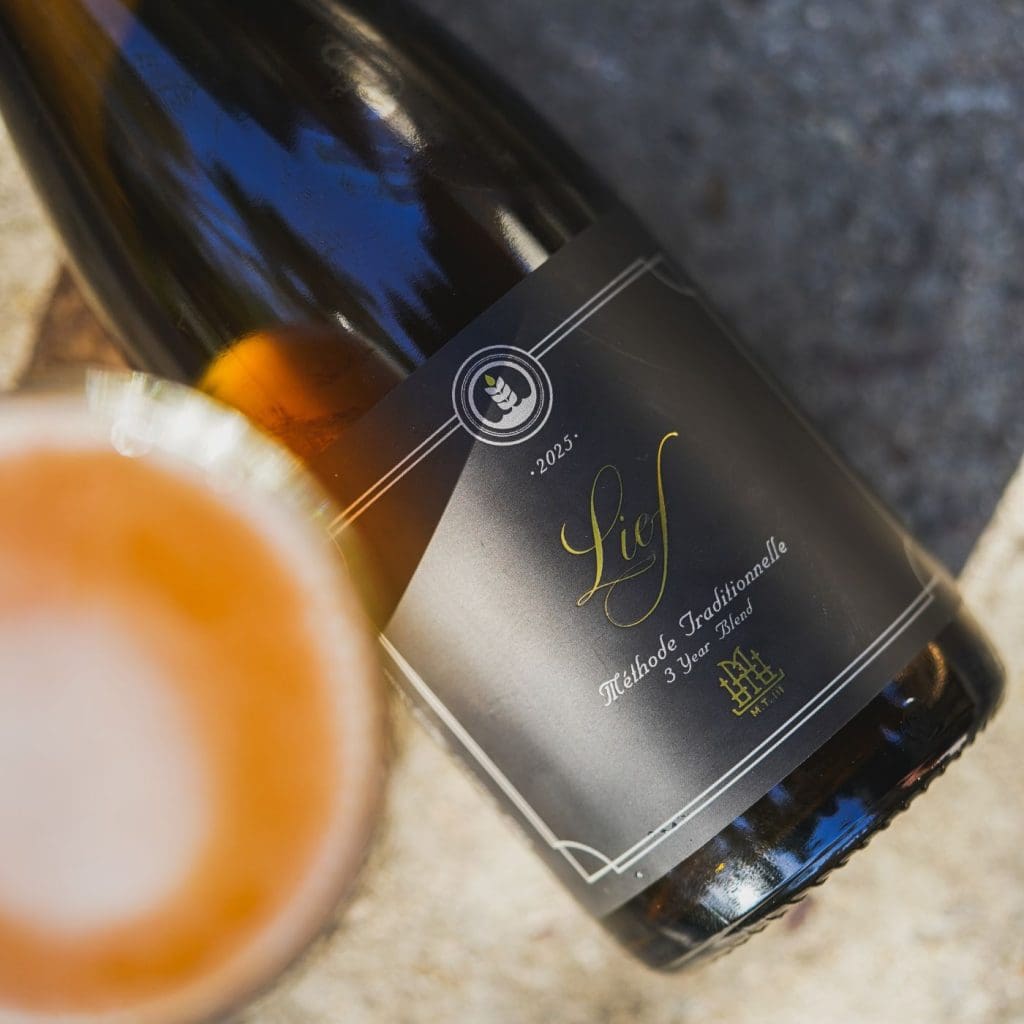 Top-down view of a bottle of Pure Project Lief Methode Traditionelle sour ale next to glass of beer
