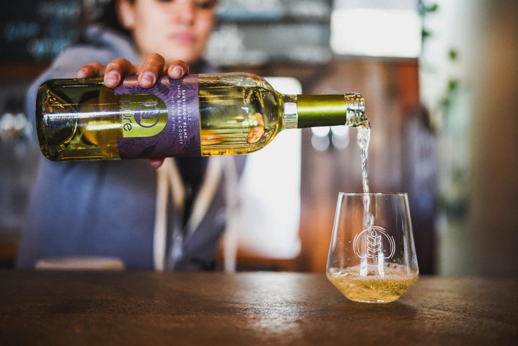 Image of woman pouring a glass of Pure Project Sauvignon Blanc